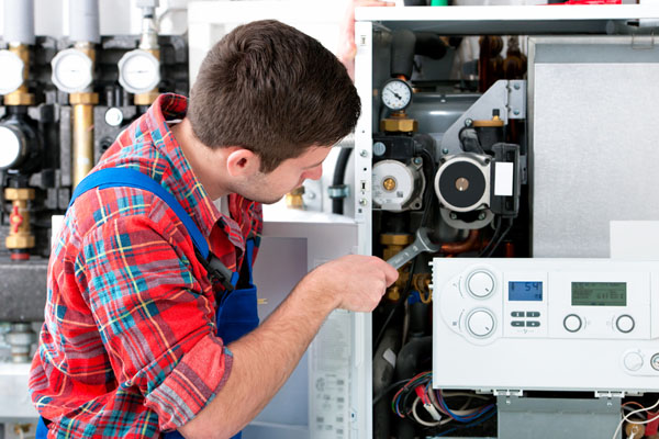 HVAC technician inspecting and repairing boiler controls in West Jordan
