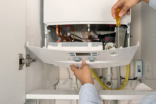 HVAC technician repairing an indoor boiler in West Jordan