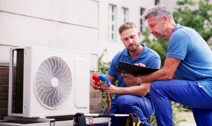 HVAC technicians installing an outdoor air conditioning unit in West Jordan