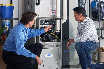 65df8c11f3e4c468cbd351a5_furnace repair vs replacement – Copy HVAC technician explaining furnace repair and maintenance to a homeowner in West Jordan, UT